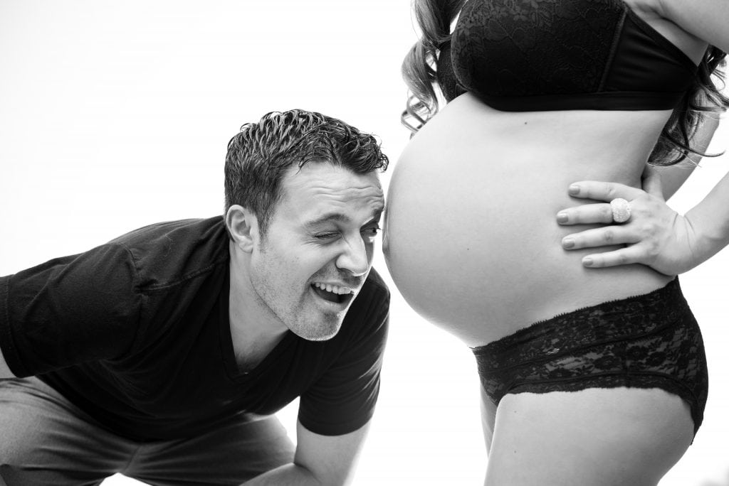 in maternity photos future dad pretends to see baby in womb through wife's belly button