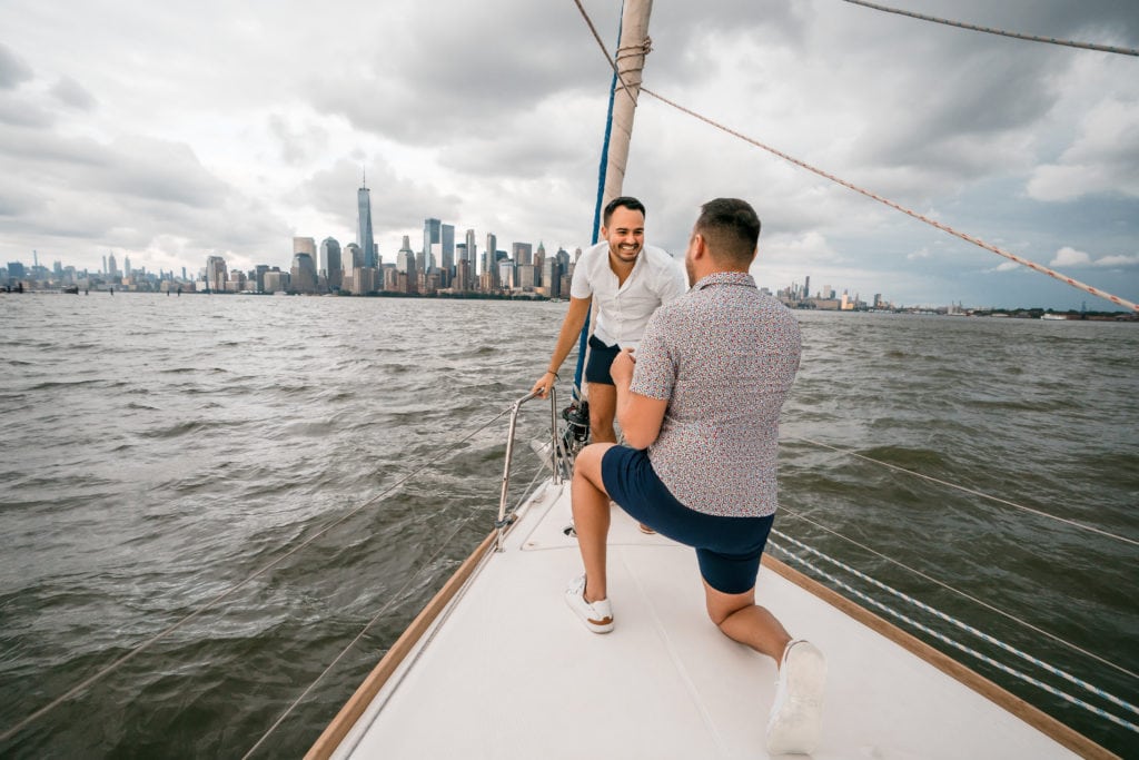 a gentleman on his knee proposing to his boyfriend on the hudson river