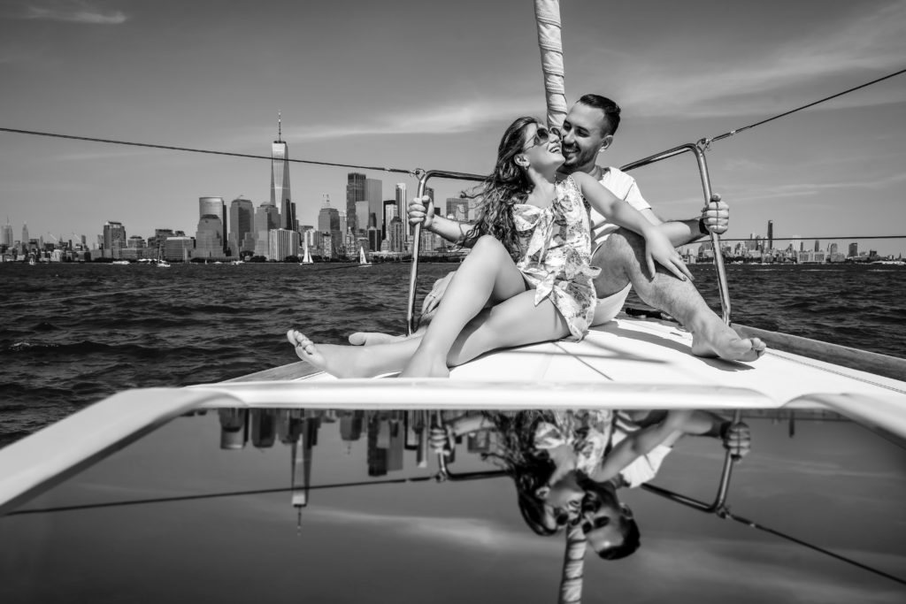 Couple smiles sitting on a boat against a NYC backdrop