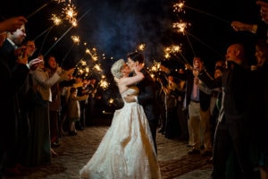 Lesbian couple just married kissing at night under an arch of sparklers in Far Hills NJ.