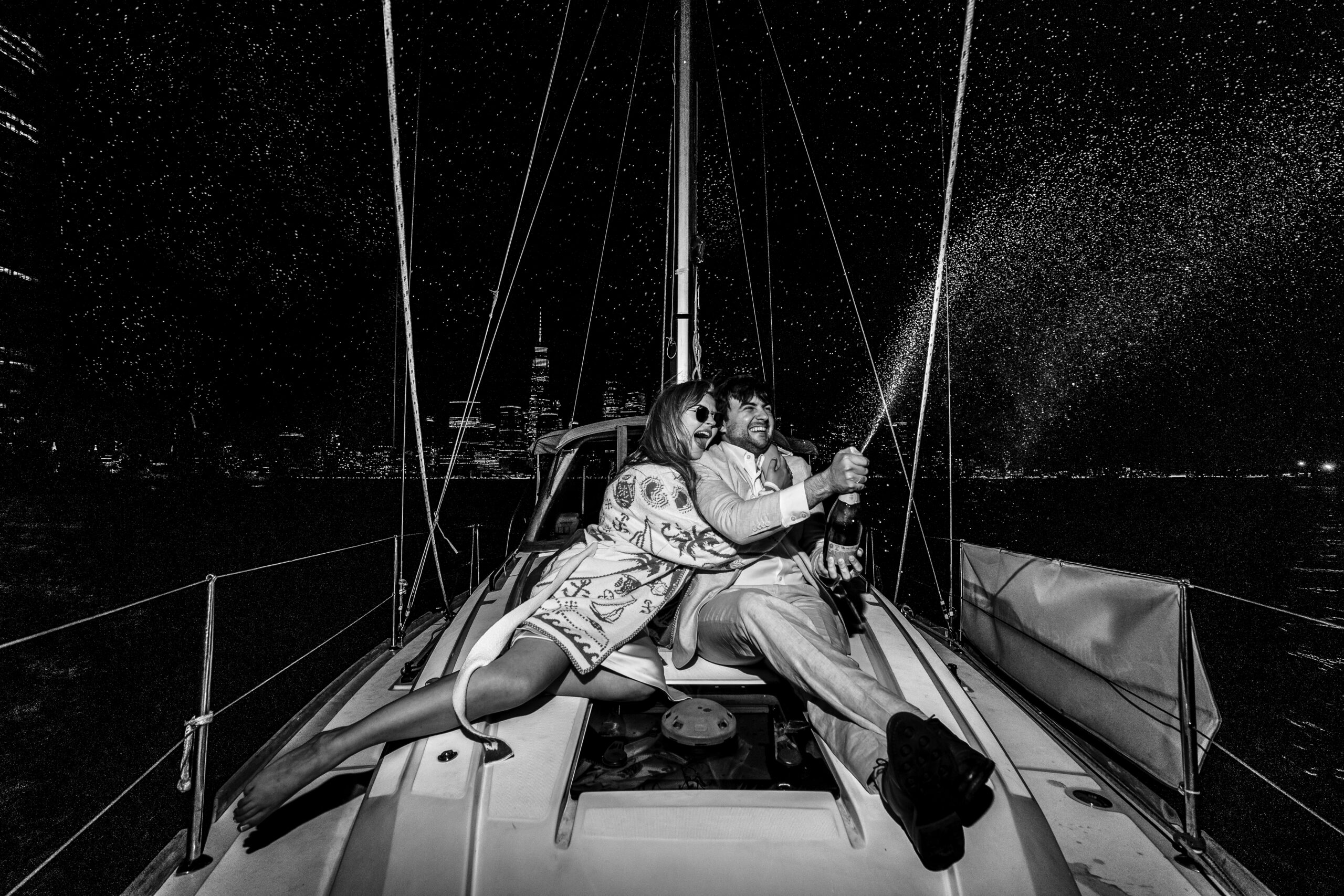 couple gets engaged on a yacht on the hudson river and spray champagne while celebrating in a photo